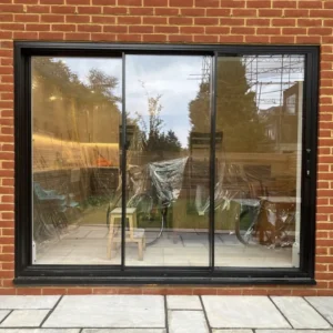 Black aluminium sliding doors on London brick rear wall