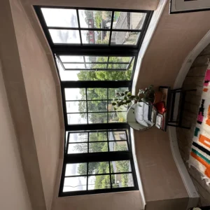 Black aluminium Crittall-style window with garden view, London