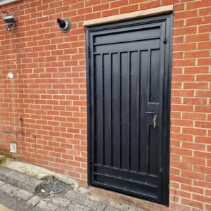 Black metal security door brick wall London property