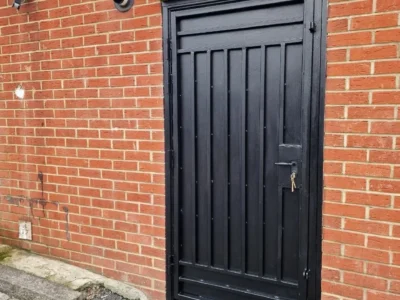 Black metal security door brick wall London property