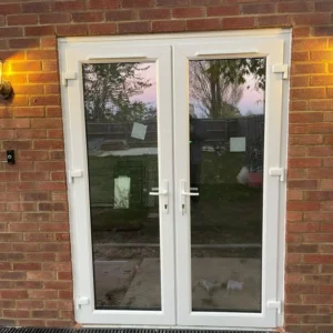 White uPVC French doors on London brick exterior at dusk