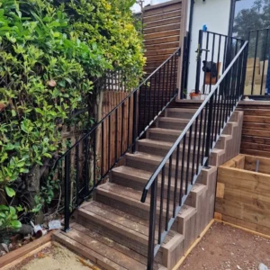 Black metal staircase balustrade beside garden, London