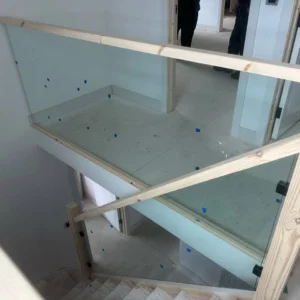 Frameless glass stairwell balustrade being fitted, London