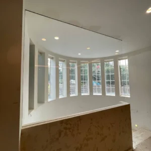 Frameless glass partition above curved bay window, London