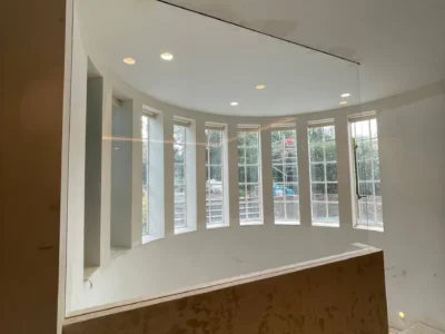 Frameless glass partition above curved bay window, London