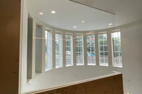 Frameless glass partition above curved bay window, London