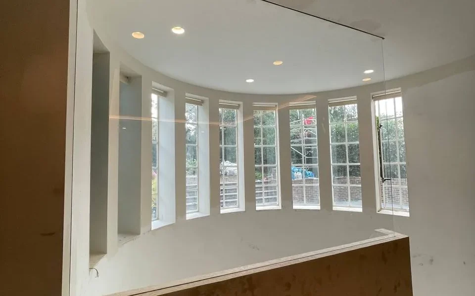 Frameless glass partition above curved bay window, London