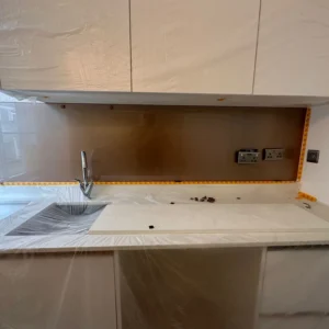 Bronze glass splashback being fitted, London kitchen