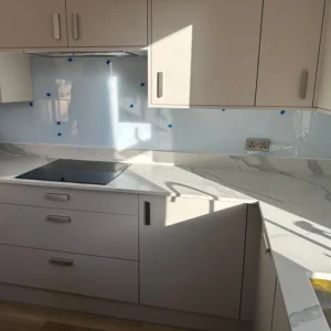 Blue glass splashback above induction hob, London kitchen