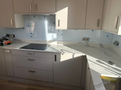 Blue glass splashback above induction hob, London kitchen