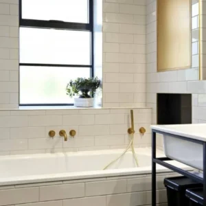 Bathroom with brass-framed mirror and black window, London