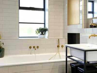 Bathroom with brass-framed mirror and black window, London