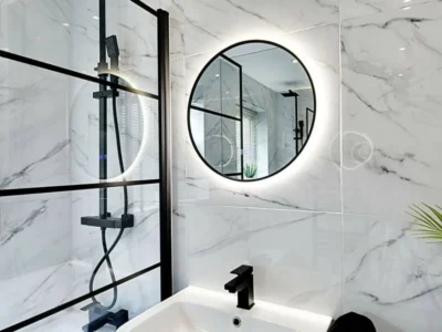 Round backlit bathroom mirror with black shower screen, London