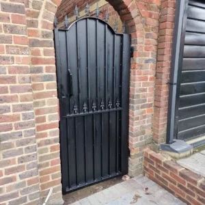 Black metal side gate in brick archway, London