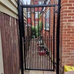 Black metal garden side gate between fences, London