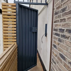 Anthracite metal side gate against brick wall, London