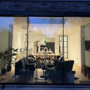 Black aluminium sliding doors at dusk, London garden extension