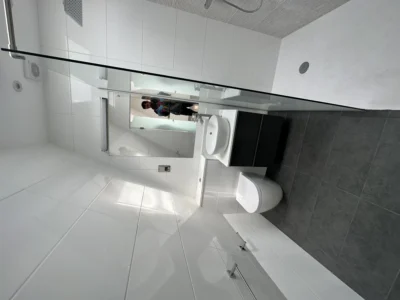 Frameless glass shower screen in modern white London bathroom
