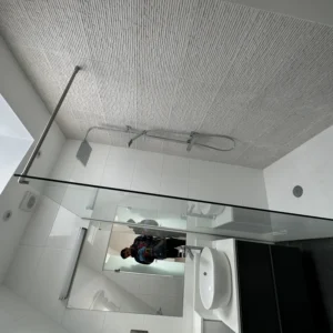 Frameless glass shower screen below skylight in London bathroom