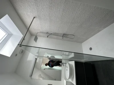 Frameless glass shower screen below skylight in London bathroom