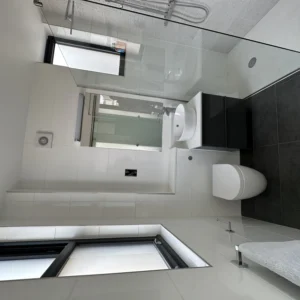Glass shower screen and aluminium window in London bathroom