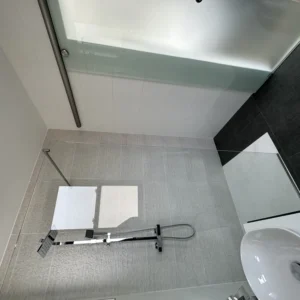 Glass shower screen in compact tiled London bathroom