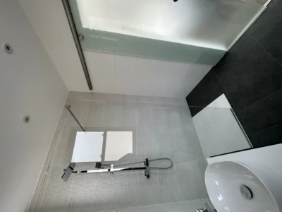 Glass shower screen in compact tiled London bathroom