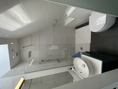 Glass shower screen in grey-tiled London loft bathroom