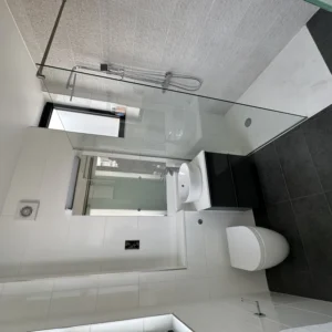 Glass shower screen in monochrome tiled London bathroom