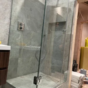 Frameless glass shower enclosure in marble bathroom, London