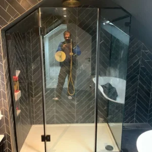 Frameless glass shower enclosure, dark tiled London bathroom