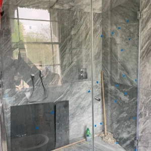 Frameless glass shower screen on marble wall, London