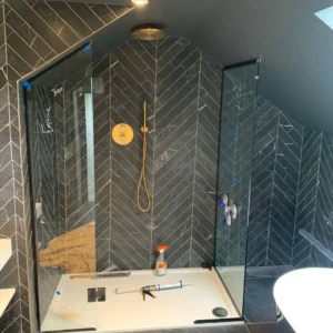 Frameless glass shower enclosure, black tiled London bathroom
