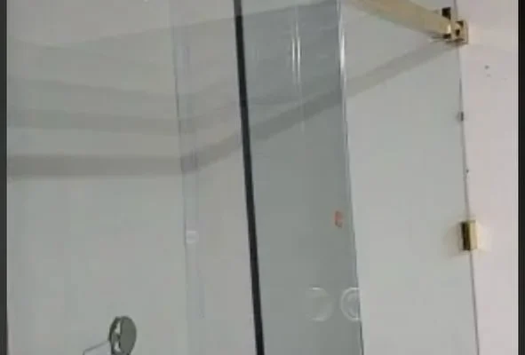 Sliding glass shower door with brass track, London