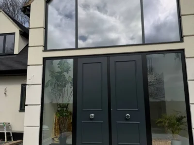 Apex structural glazing around black front doors, London