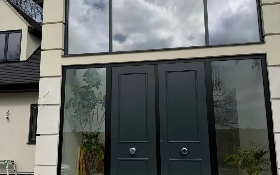 Apex structural glazing around black front doors, London